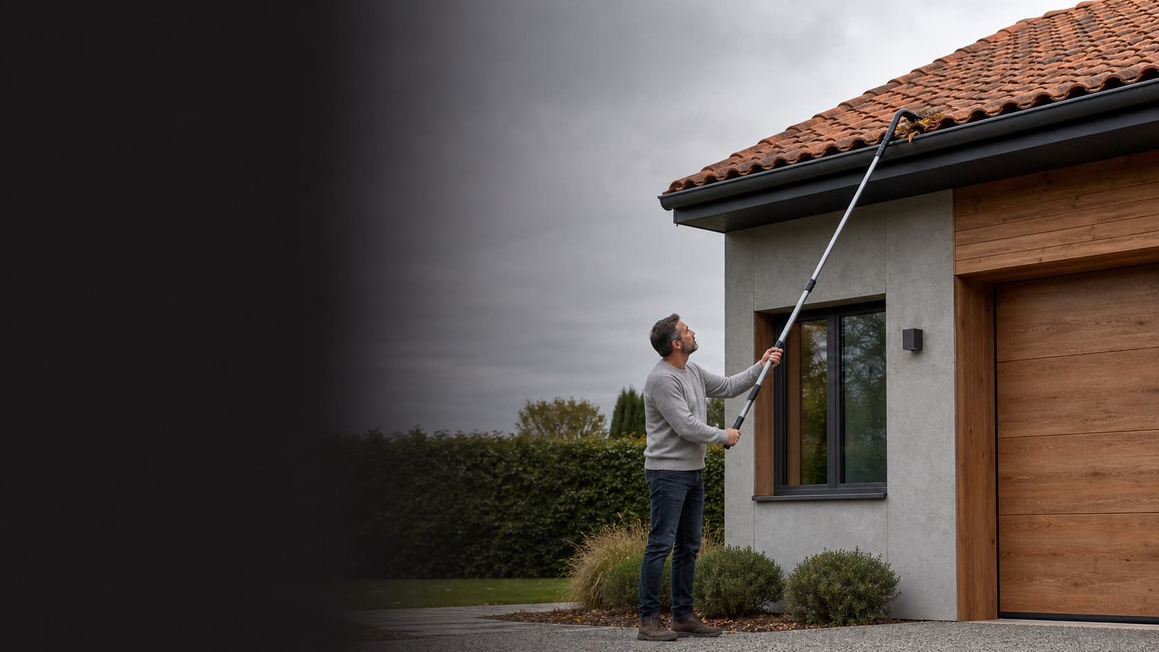 Homeowner using a telescopic pole from level ground to maintain a gutter